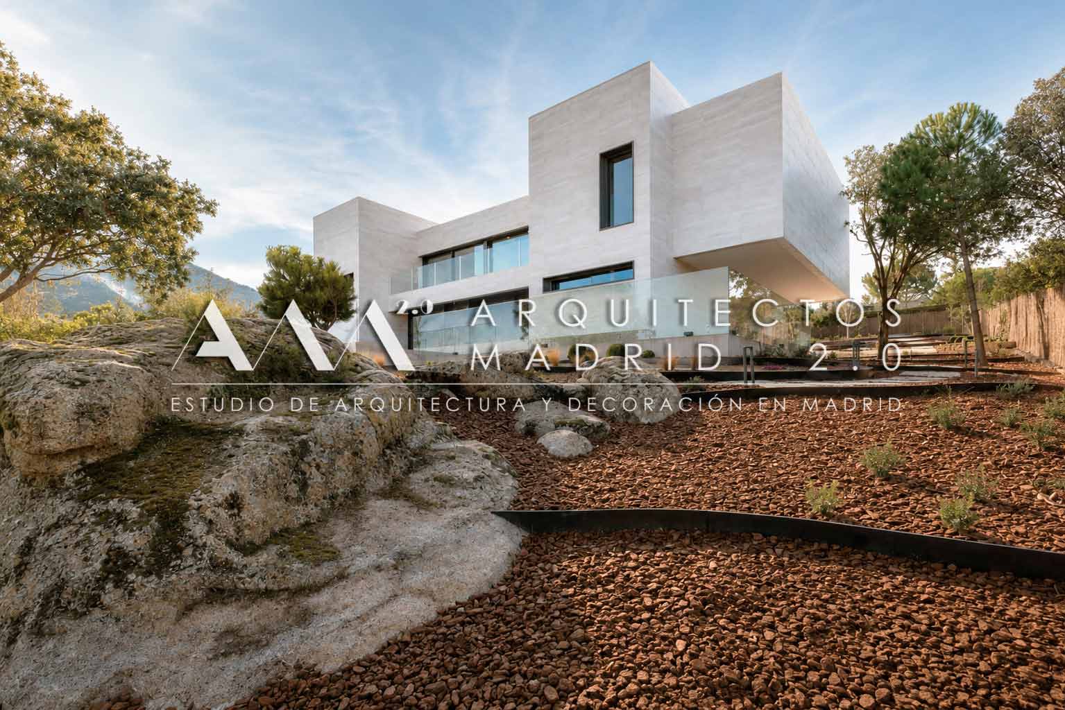 Vivienda unifamiliar minimalista adaptada al terreno, con fachada de piedra y jardín de rocalla