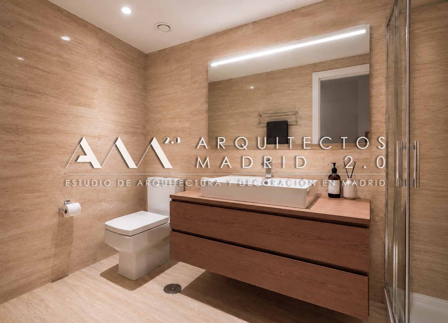 Baño con mueble suspendido de madera y revestimiento de travertino en vivienda de 380 m² en Madrid
