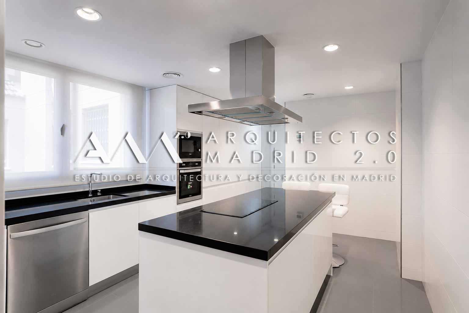 Cocina con isla, mobiliario blanco y encimera negra en vivienda de 380 m² en Chamberí, Madrid