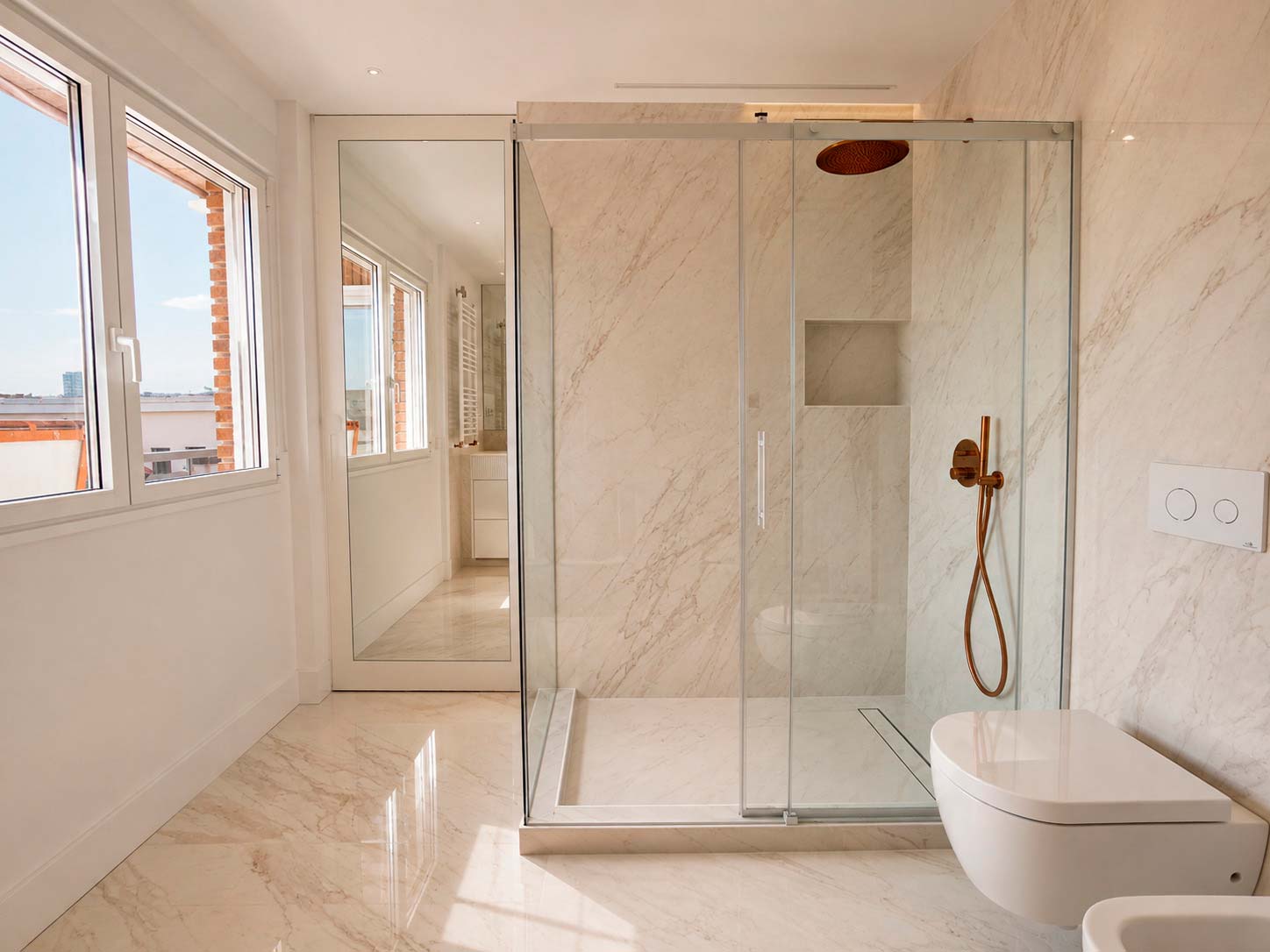 Baño principal con ducha, ventana y abundante luz natural en la reforma integral de Fuencarral, Chamberí