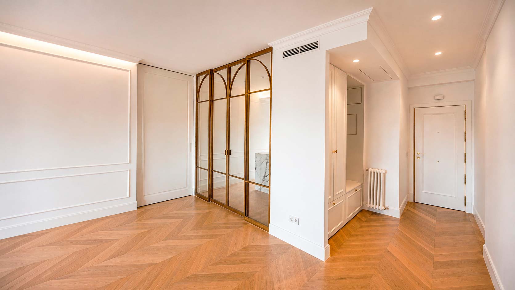 Distribuidor con gran puerta corredera de suelo a techo y cristalera de cocina en la vivienda reformada de Fuencarral, Chamberí