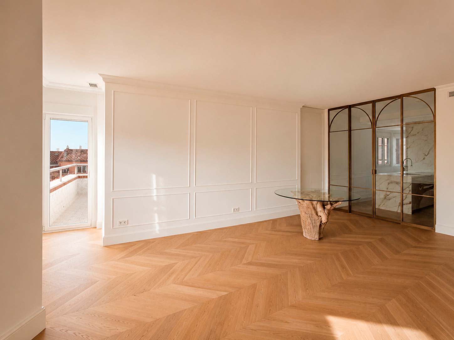 Parquet en espiga, molduras y acceso a terraza en el salón de la vivienda reformada en la calle Fuencarral, Chamberí