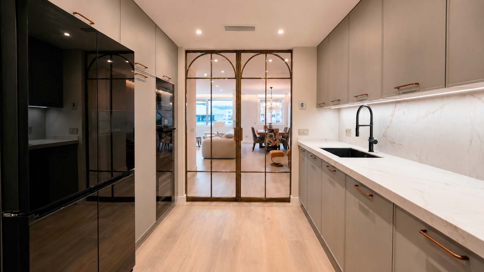 Cocina independiente con cristalera de formas curvas y acabado oro viejo en reforma integral de ático dúplex en calle Orense, Madrid