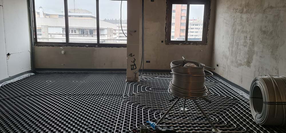Circuitos de suelo radiante instalados en el salón durante la reforma integral de vivienda en calle Orense, Madrid