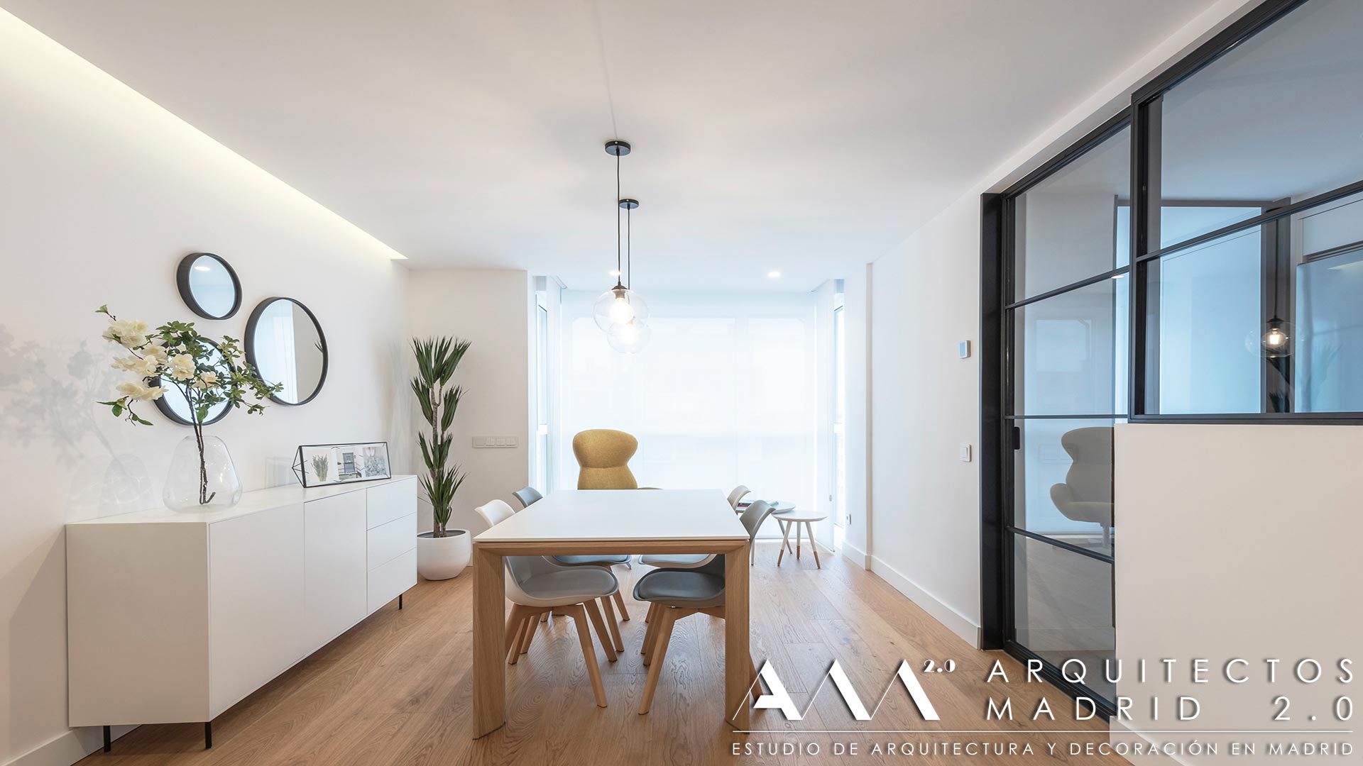 Comedor con carpintería acristalada hacia la cocina después de la reforma integral de una vivienda en Las Rosas, Madrid