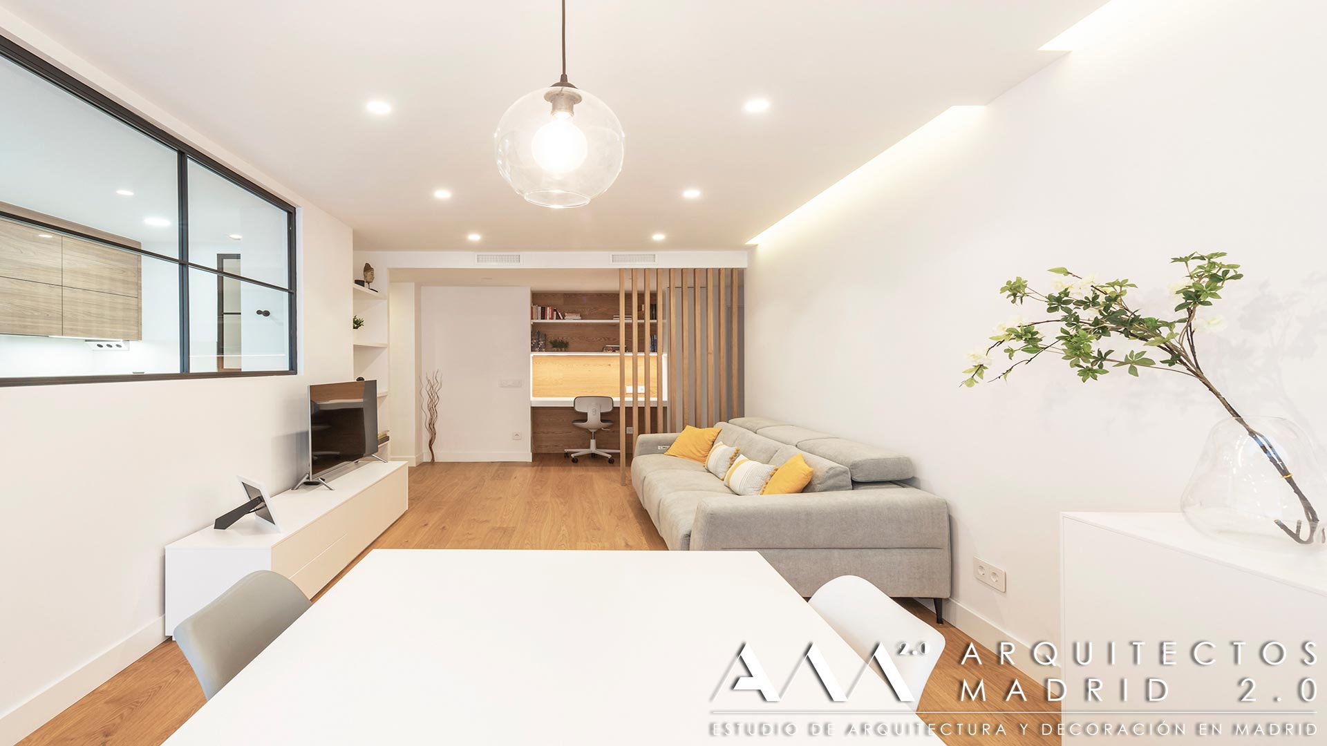 Salón comedor con cocina acristalada y despacho integrado tras la reforma integral de una vivienda de 100 m² en Las Rosas, Madrid