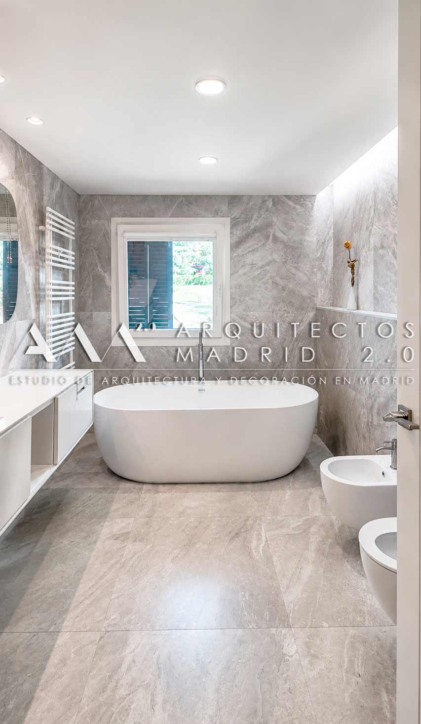 Baño principal con bañera exenta y revestimiento pétreo en una vivienda unifamiliar reformada en Boadilla