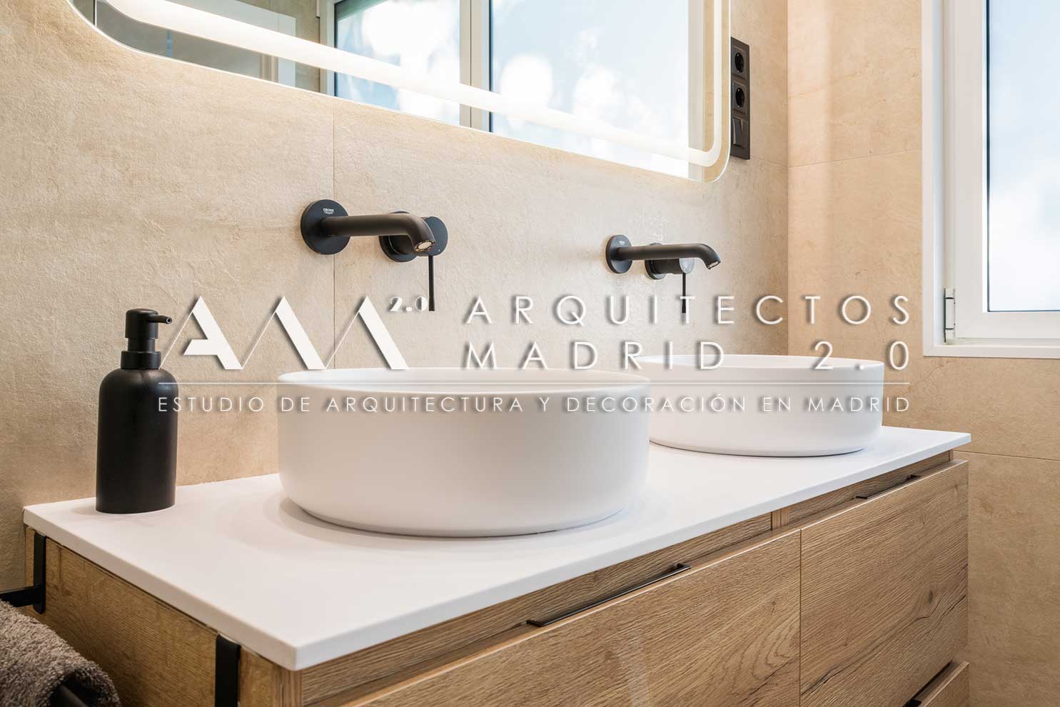 Baño con lavabo doble, mueble de madera, espejo iluminado y griferías negras en vivienda reformada
