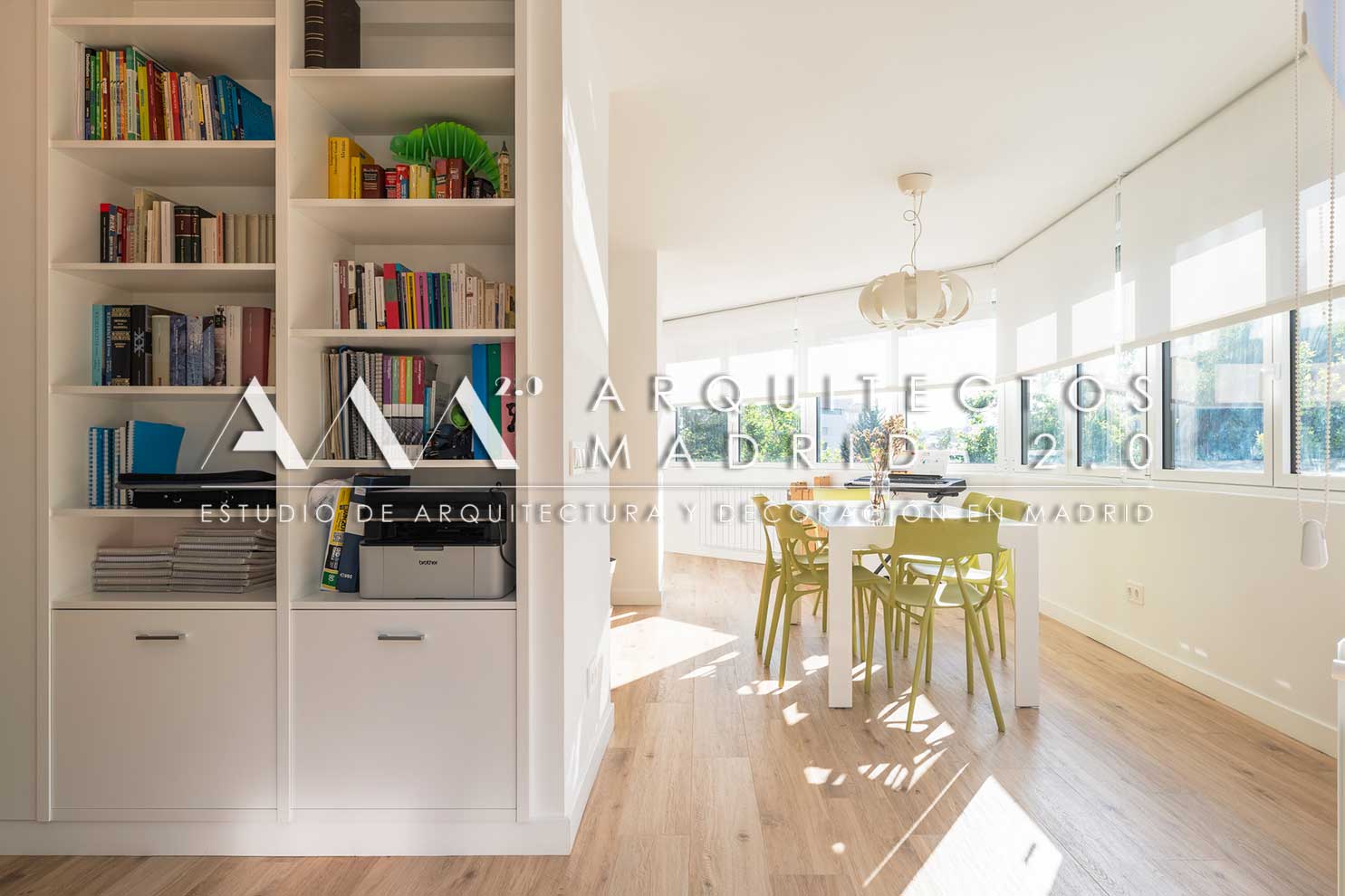 Estantería blanca a medida conectada con comedor luminoso y grandes ventanales en vivienda de Chamartín