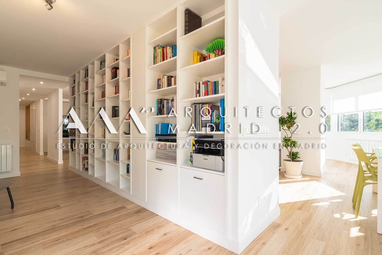 Biblioteca a medida que conecta la circulación con el comedor luminoso de la vivienda reformada