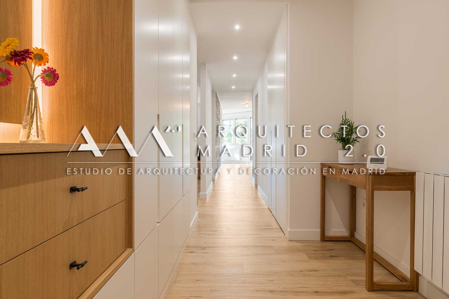 Pasillo reformado con mueble de recibidor, madera, iluminación y almacenamiento integrado en vivienda de Chamartín