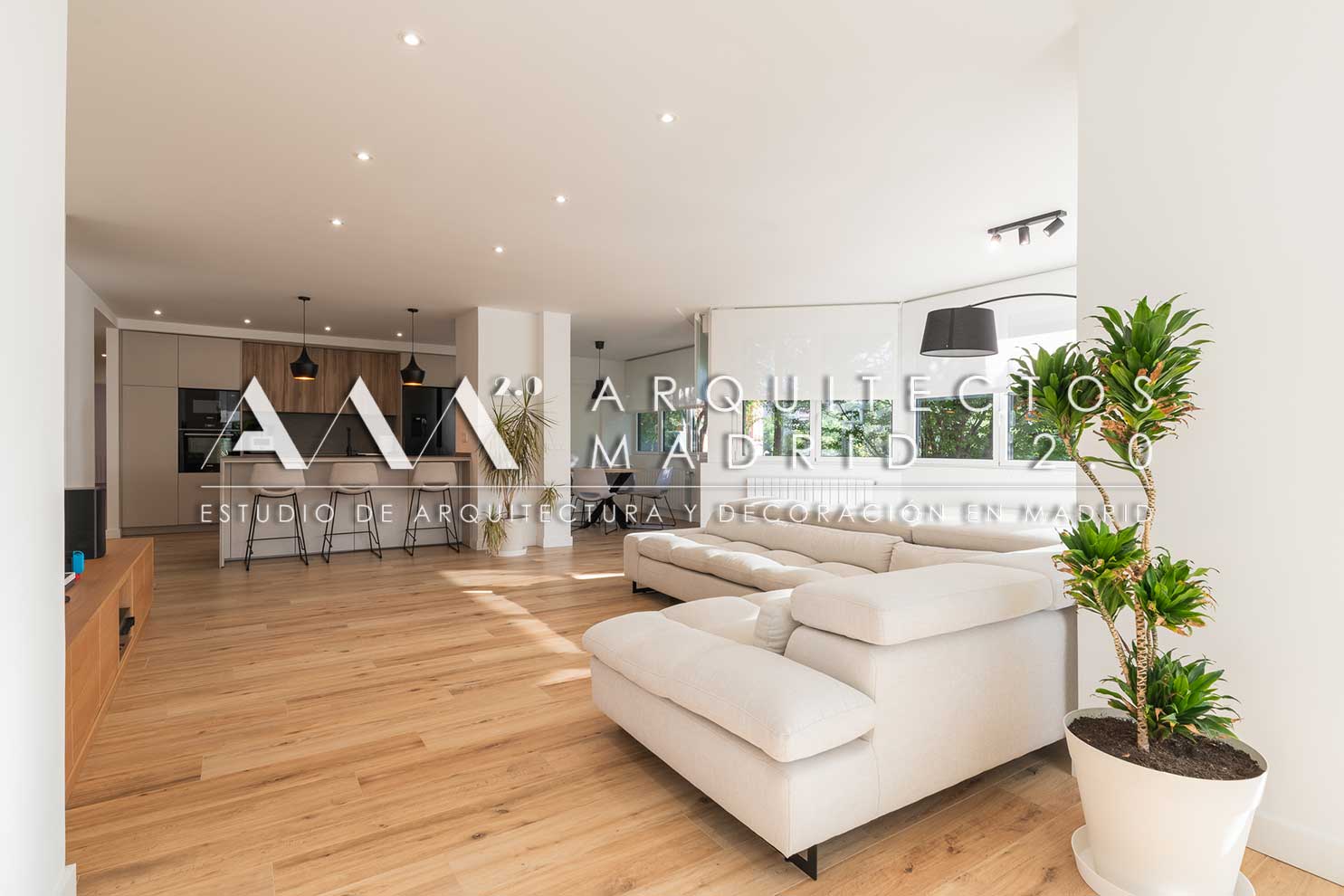 Salón con sofá blanco conectado con cocina abierta en vivienda familiar reformada en Chamartín
