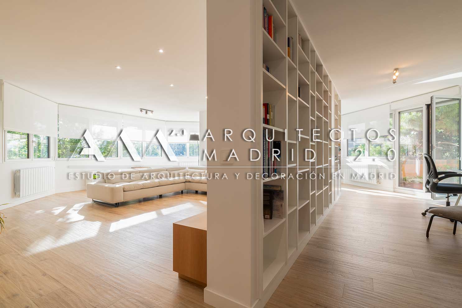 Salón reformado con sofá blanco, carpintería de madera y biblioteca integrada en vivienda de Nueva España, Chamartín