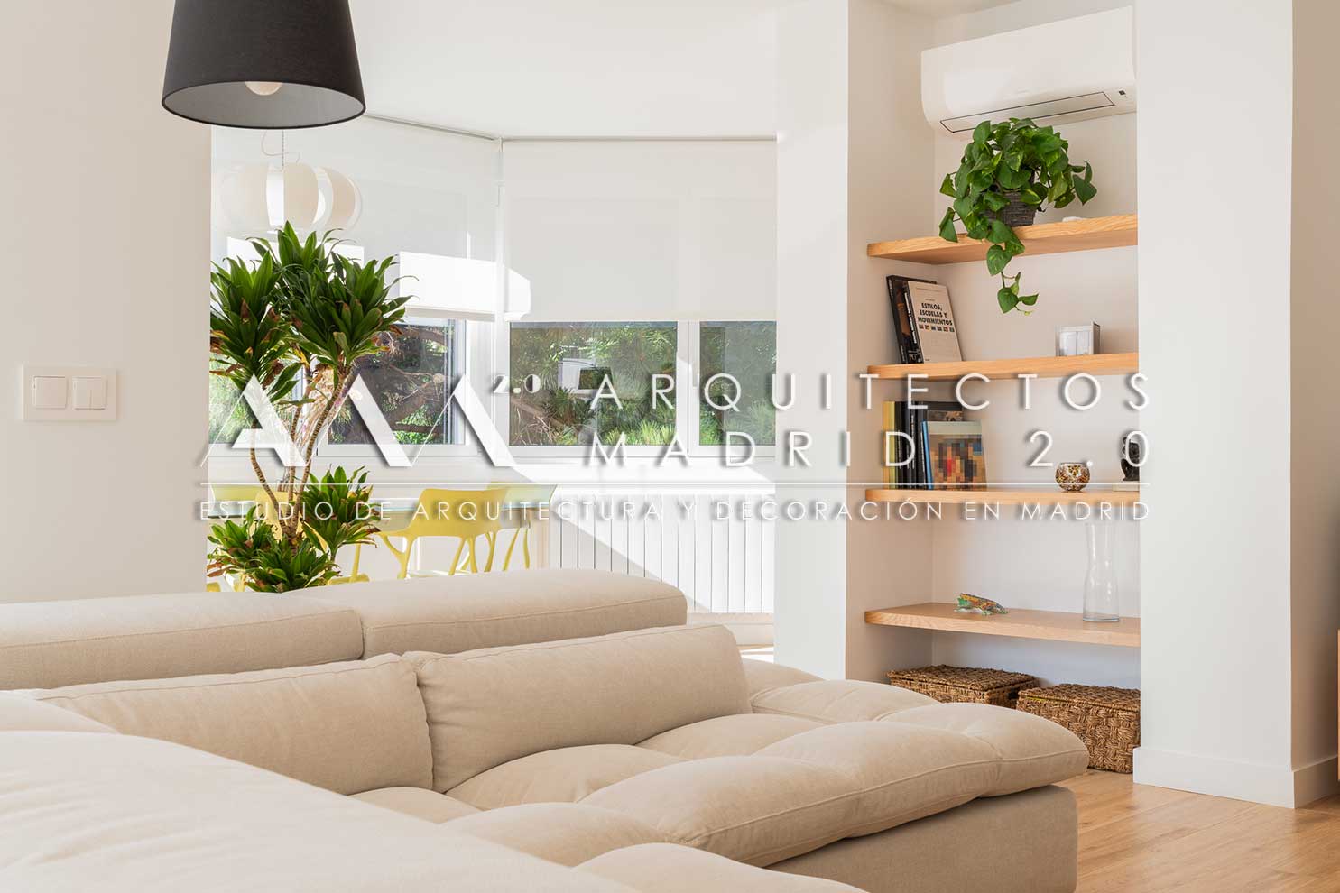Salón con sofá claro, estanterías y carpinterías de madera a medida en vivienda reformada en Nueva España