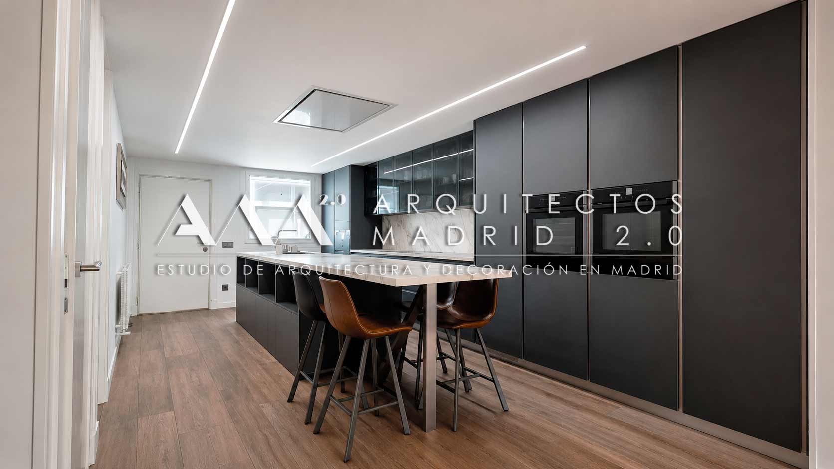 Cocina negra con gran isla central tras la reforma integral de una vivienda unifamiliar en Boadilla del Monte