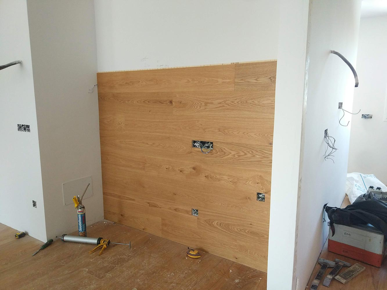 Montaje de revestimiento de madera coordinado con mecanismos eléctricos durante una reforma integral de vivienda en Madrid