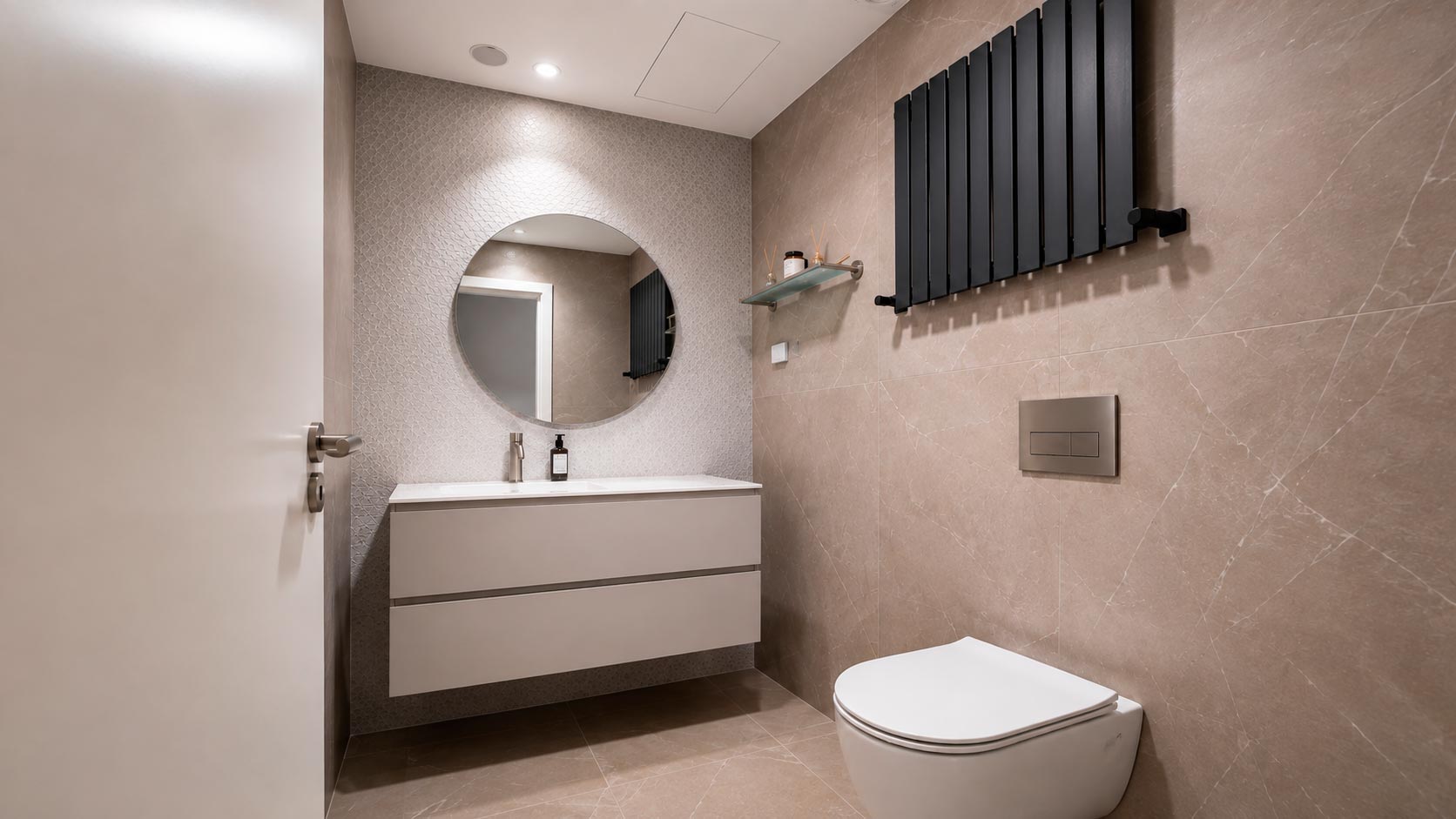 Segundo baño en suite con lavabo suspendido, espejo circular y sanitario suspendido en vivienda reformada de Jorge Juan