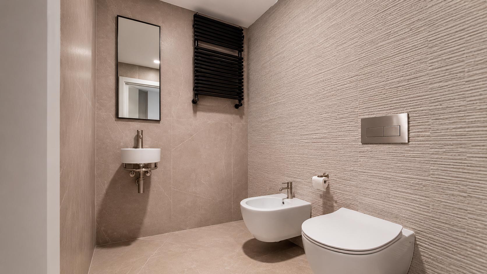 Aseo de cortesía con lavabo compacto, sanitario y bidé suspendidos en reforma integral de vivienda en Jorge Juan, Madrid
