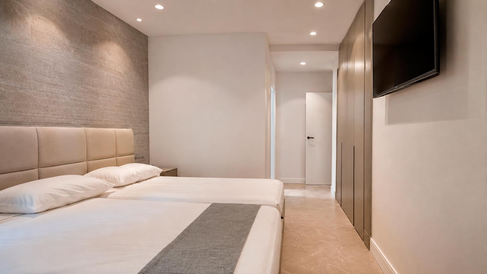 Dormitorio con dos camas grandes y frente completo de armarios en reforma integral de vivienda en Jorge Juan, Madrid