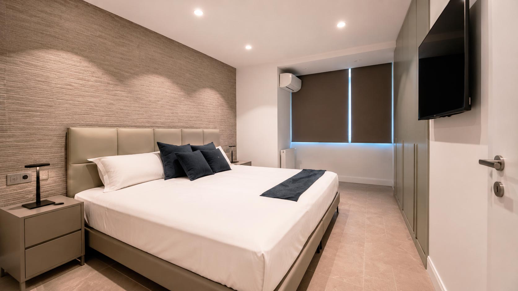 Dormitorio en suite con armarios de pared completa e iluminación empotrada en vivienda reformada de Jorge Juan, Madrid