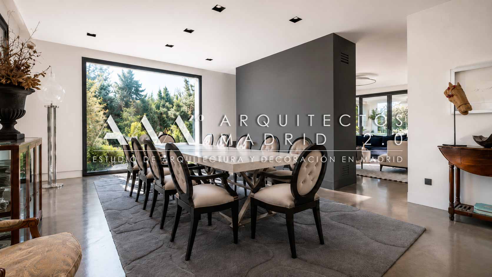 Comedor interior abierto hacia el jardín mediante grandes ventanales