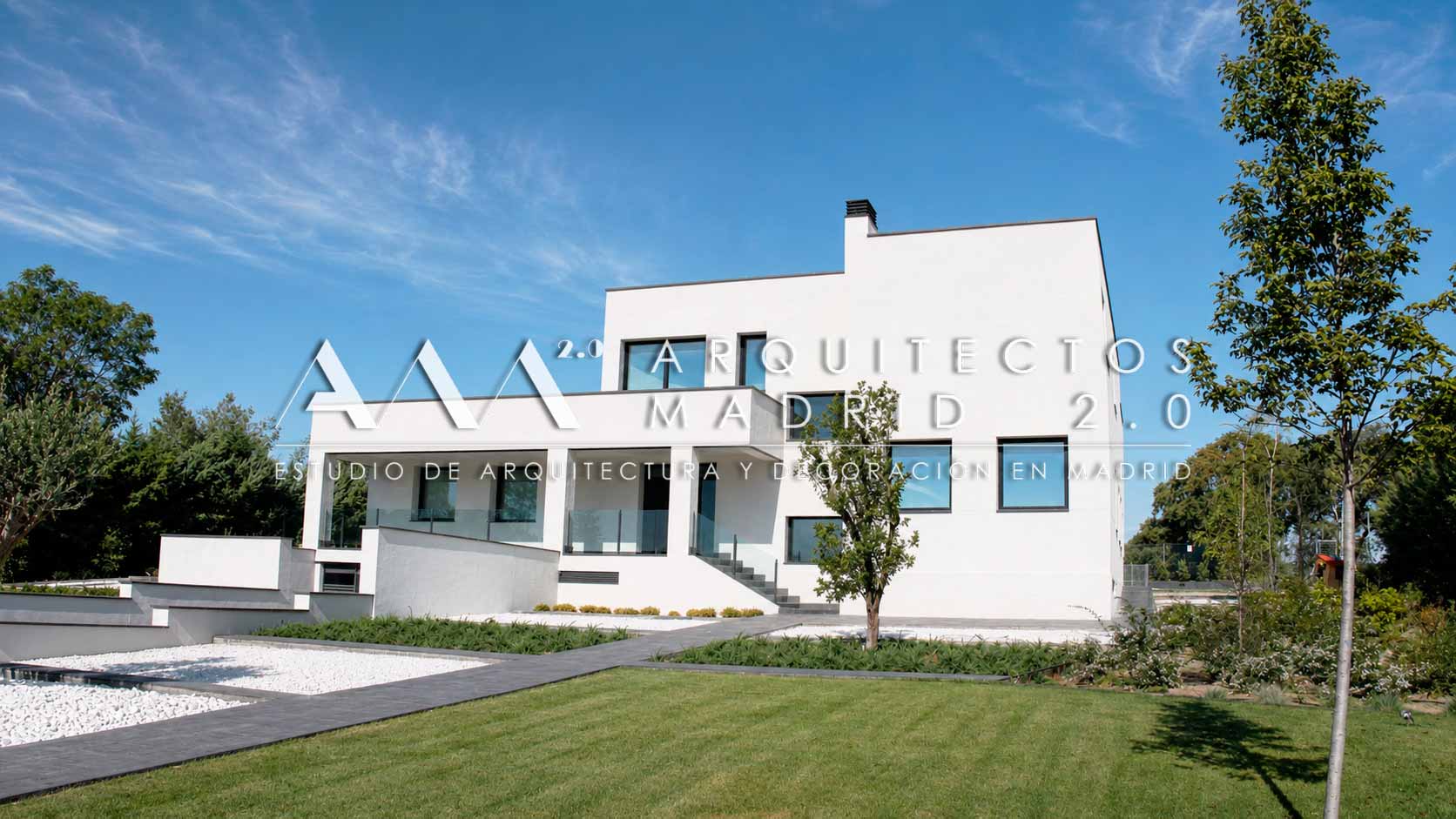 Fachada blanca de vivienda unifamiliar reformada frente a un jardín de césped