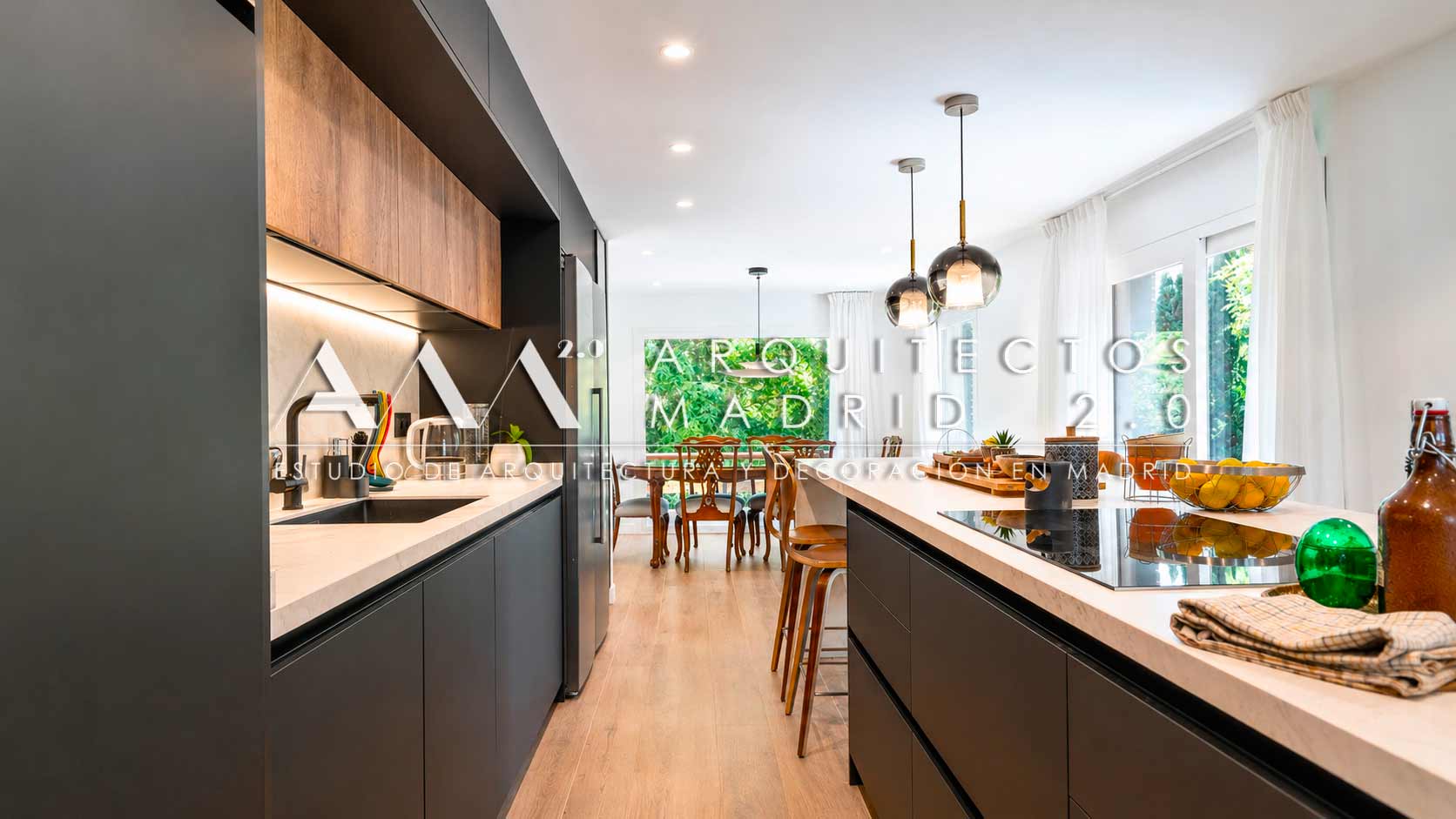 Cocina negra con isla de mármol blanco abierta al comedor en chalet reformado