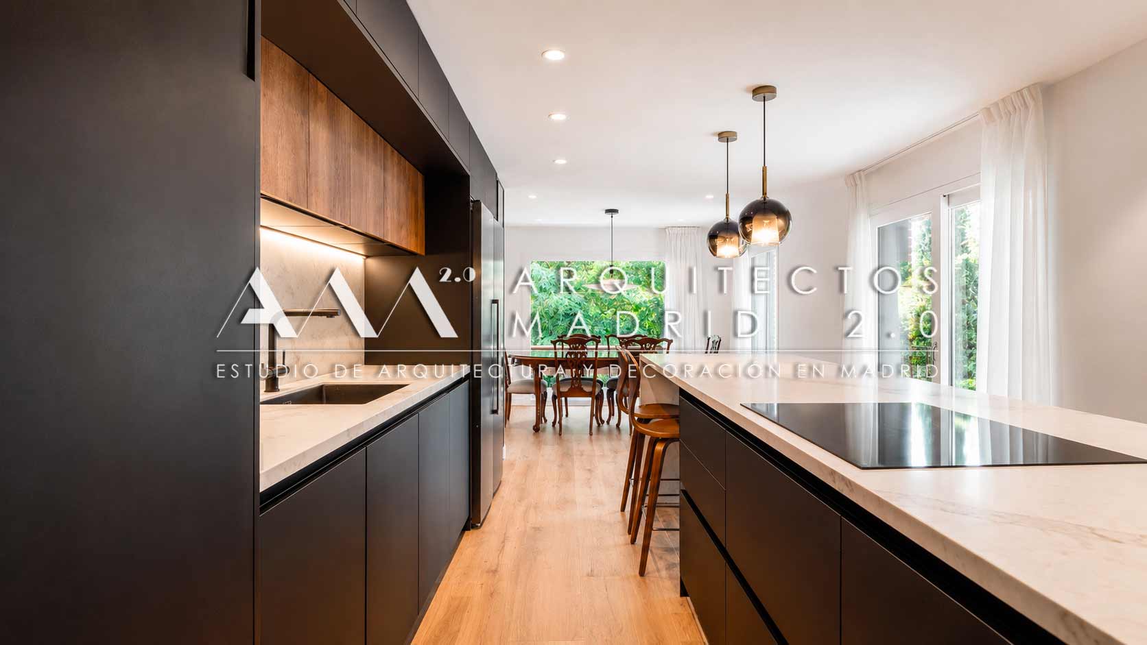 Cocina negra con pasillo e isla de mármol en reforma de vivienda unifamiliar