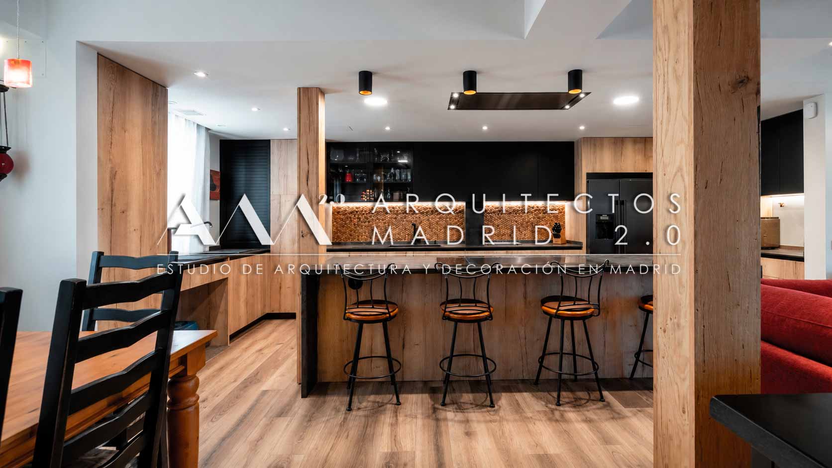 Barra de cocina con taburetes negros y mobiliario de madera en vivienda unifamiliar reformada