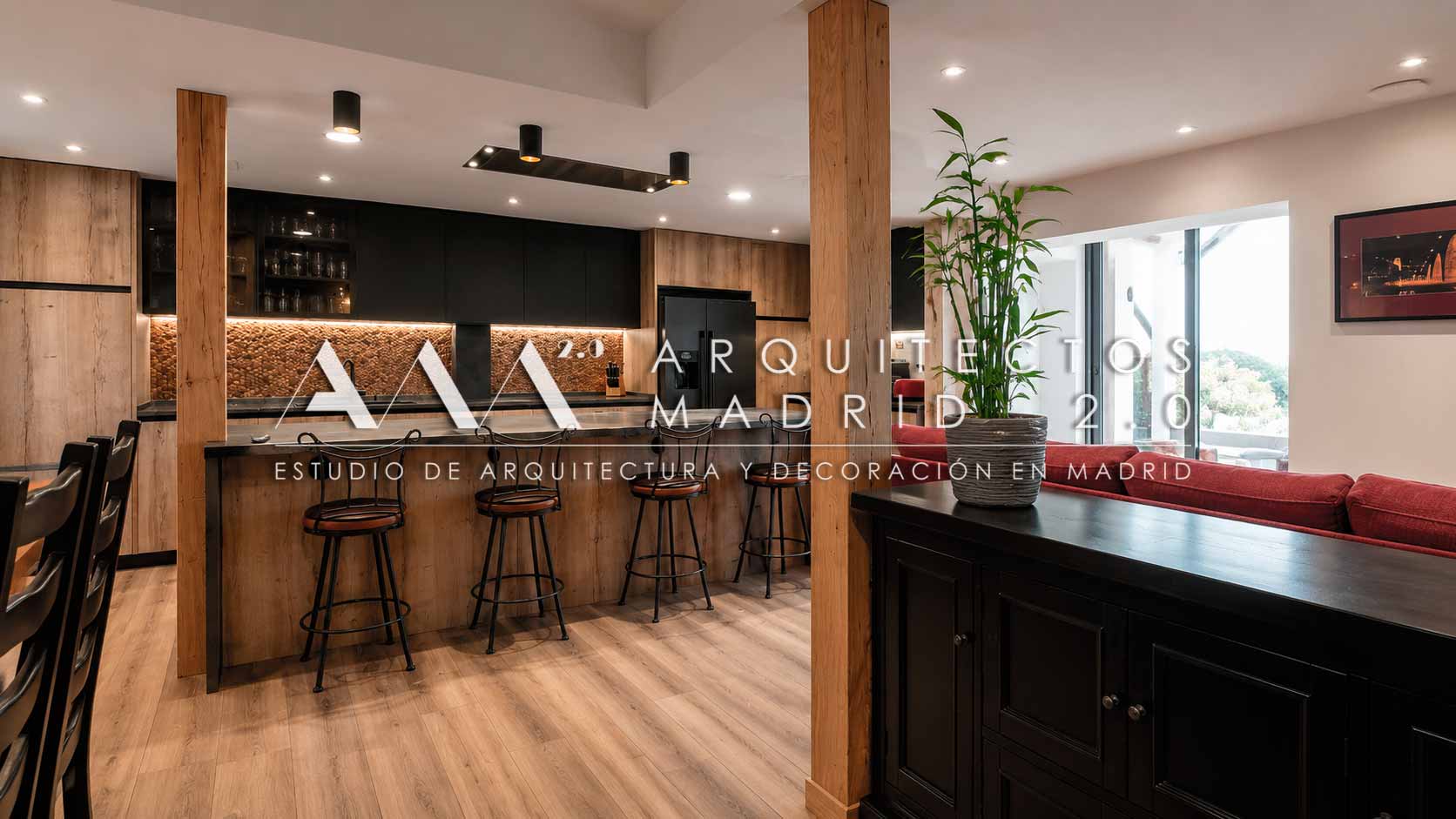 Cocina de madera con gran isla abierta hacia salón rojo en rehabilitación integral de vivienda unifamiliar en Madrid
