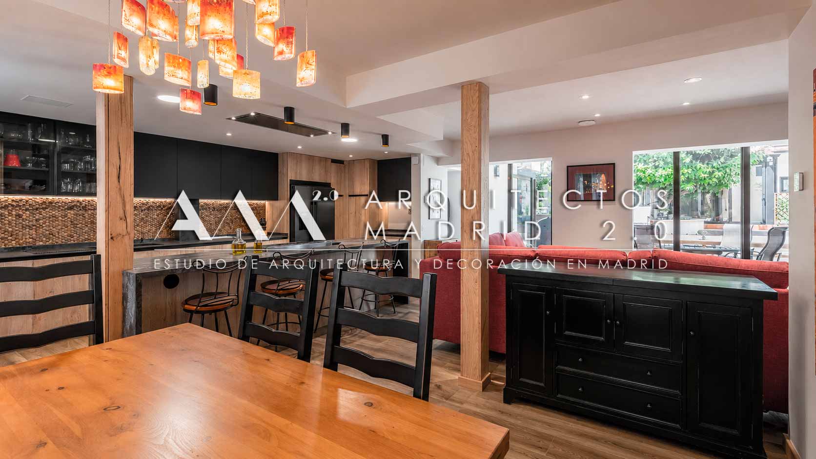 Cocina de madera con isla negra abierta hacia el salón de una vivienda unifamiliar en Madrid