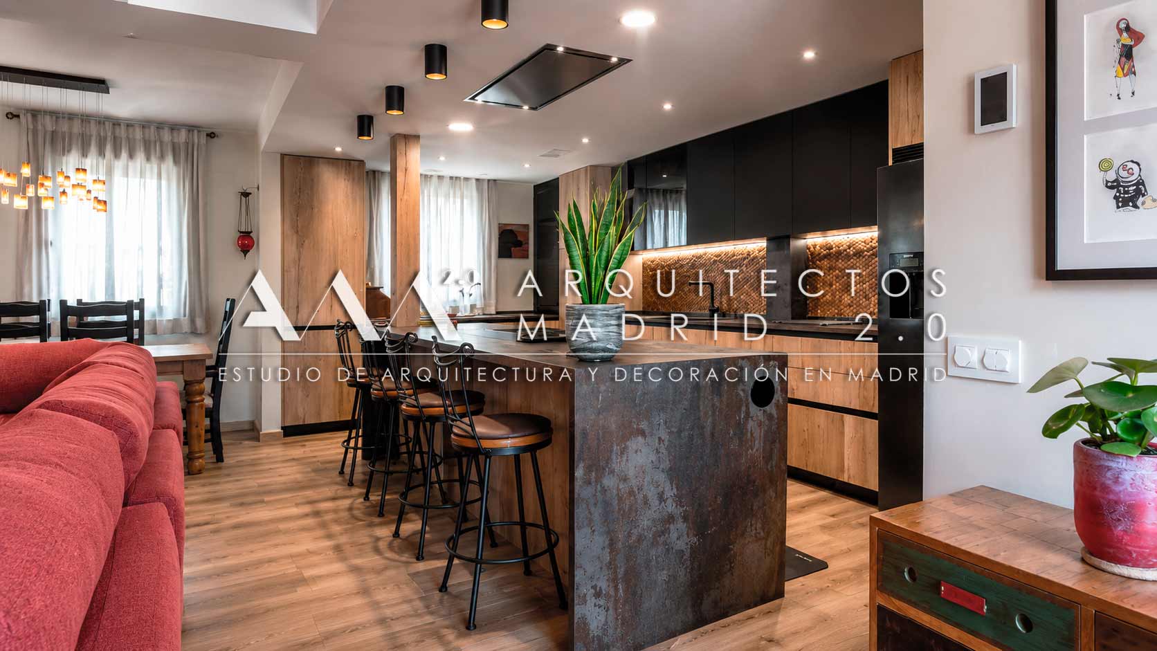 Salón y cocina con gran isla y taburetes negros en vivienda unifamiliar rehabilitada