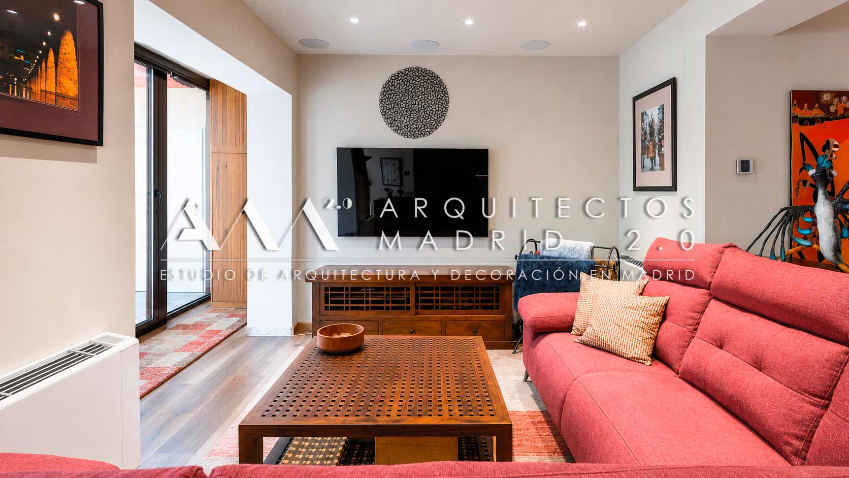 Salón con sofá rojo y mueble de televisión tras la rehabilitación de una vivienda unifamiliar en Madrid